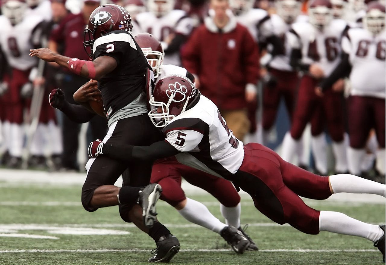 contact-img Exciting tackle during an American football game highlighting teamwork and athletic skill.