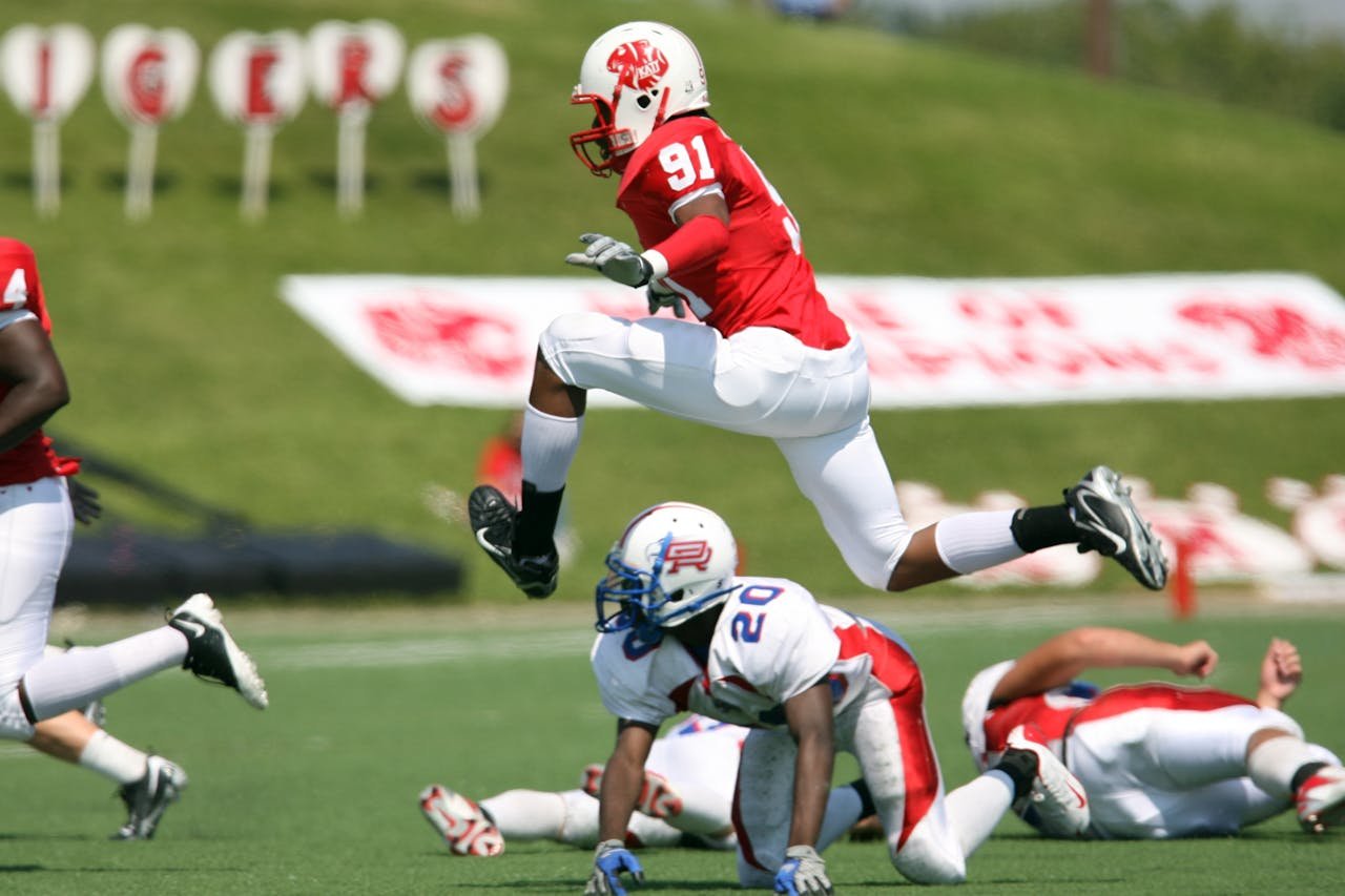 my-qualifications High-energy American football action with players in motion on the field during a daytime match.