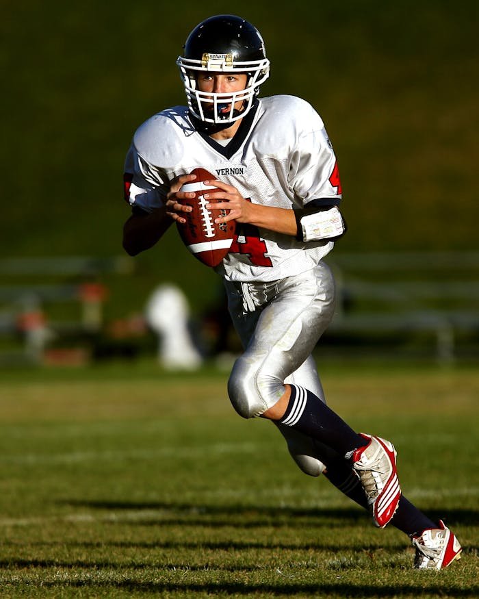 services-04 A focused young athlete playing quarterback during a daytime football game.