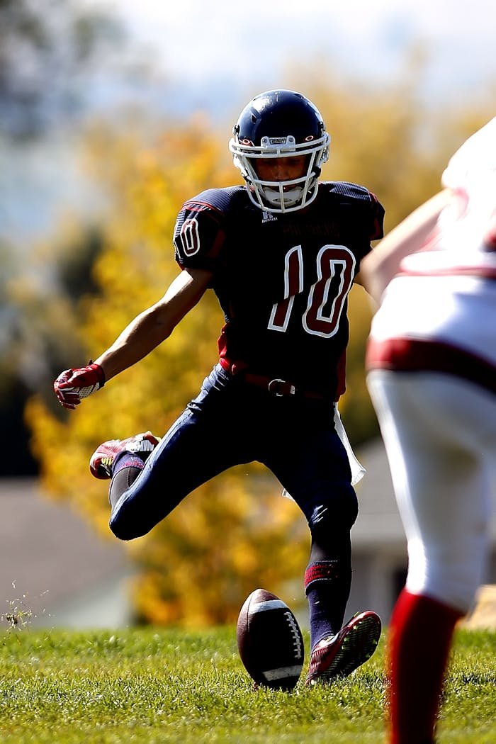 services-03 Action shot of a football player kicking the ball on a bright day in a stadium setting.